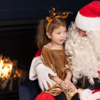 Little girl dressed as a reindeer on Santa's lap